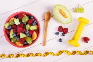Meyve salatası ve halter, sağlıklı yaşam ve beslenme kavramı ile şerit metre