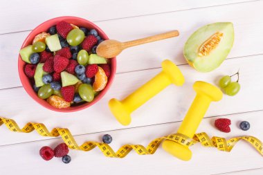Taze meyve salatası ve santimetre dambıl, sağlıklı yaşam ve beslenme kavramı ile hazırlanmış