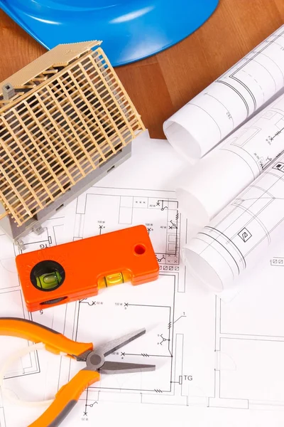 Electrical diagrams, orange work tools, blue helmet for engineer jobs and house under construction, building home concept