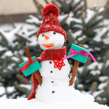 İğne yapraklı ağaç arka plan üzerinde Sevgililer günü için hediye ile dekore edilmiş kardan adam kar kaplı