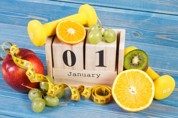 Date du 1er janvier sur le calendrier cube, fruits, haltères et ruban à mesurer, résolutions du nouvel an — Photo