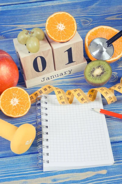Cube calendar with date of 1 January, fresh fruits, dumbbells and tape measure, new years resolutions — Stock Photo, Image