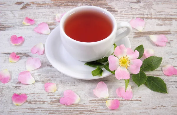 Xícara de chá e rosa selvagem flor no velho tabuleiro rústico — Fotografia de Stock