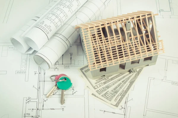 Casa en construcción, monedas dólar y claves en los diagramas eléctricos para el proyecto, la construcción de concepto de costo de la vivienda — Foto de Stock