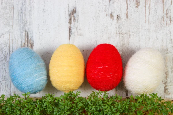 Easter eggs wrapped woolen string and green cress, copy space for text, decoration for Easter — Stock Photo, Image