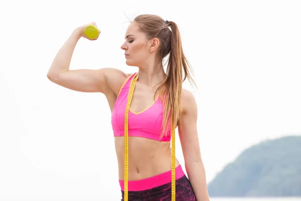 Chica delgada en ropa deportiva con centímetro haciendo ejercicio con pesas en la playa —  Fotos de Stock