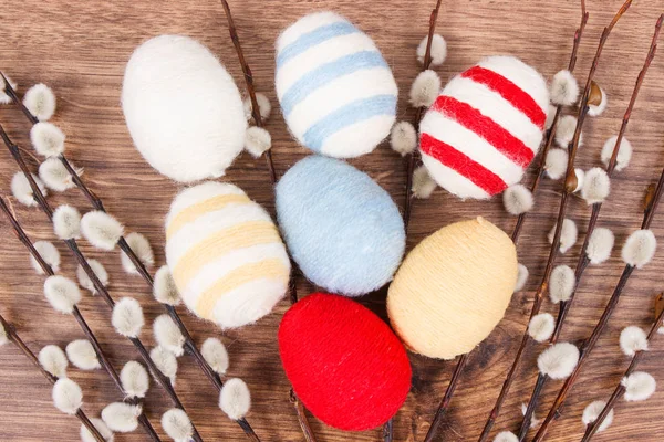 Easter catkins and eggs wrapped woolen string on rustic board, festive decoration — Stock Photo, Image