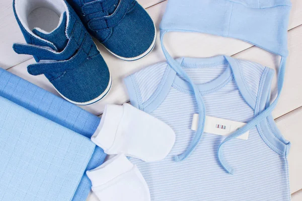 Prueba de embarazo con resultado positivo y ropa para recién nacidos, esperando concepto de bebé —  Fotos de Stock