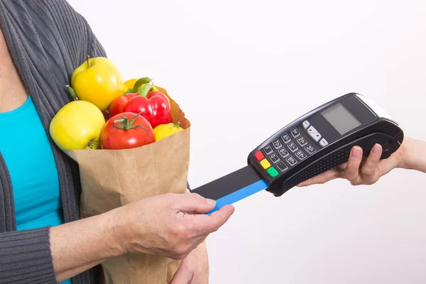 Рука пожилой женщины с помощью платежного терминала с кредитной картой, безналичная оплата покупок — стоковое фото
