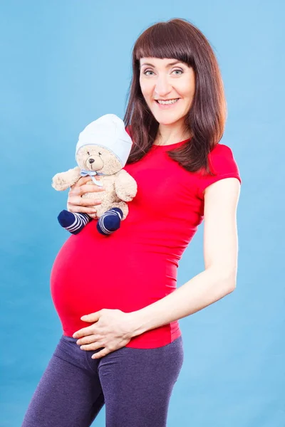 Donna incinta in possesso di orsacchiotto giocattolo a pancia, concetto di attesa per il neonato — Foto Stock