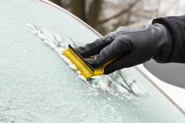 手在皮革手套刮冰或雪从汽车窗口 — 图库照片
