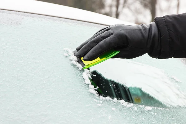 Ręka mężczyzny w rękawicę skórzaną skrobanie lodu z przedniej szyby samochodu — Zdjęcie stockowe