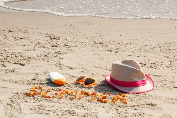 Λέξη καλοκαίρι, γυαλιά ηλίου, λοσιόν και άχυρο καπέλο ήλιο στην άμμο στην παραλία, διακοπές έννοια χρόνου — Φωτογραφία Αρχείου