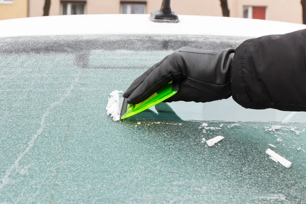 手在皮革手套刮冰或雪从汽车窗口 — 图库照片