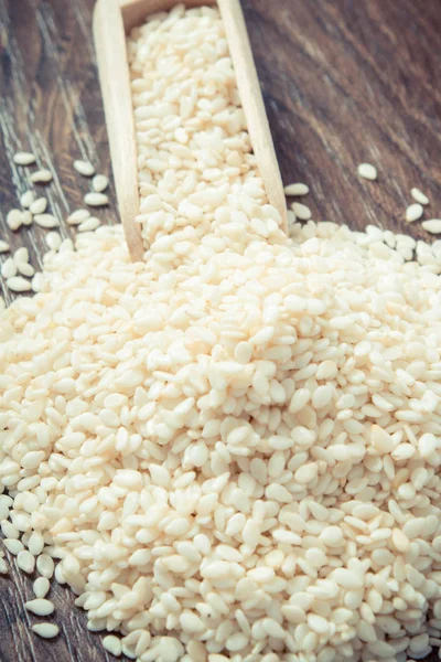 Vintage photo, Heap of sesame seeds with wooden scoop on board — Stock Photo, Image