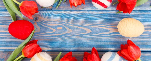 Marco de huevos de Pascua y tulipanes rojos frescos en las tablas, decoración festiva — Foto de Stock