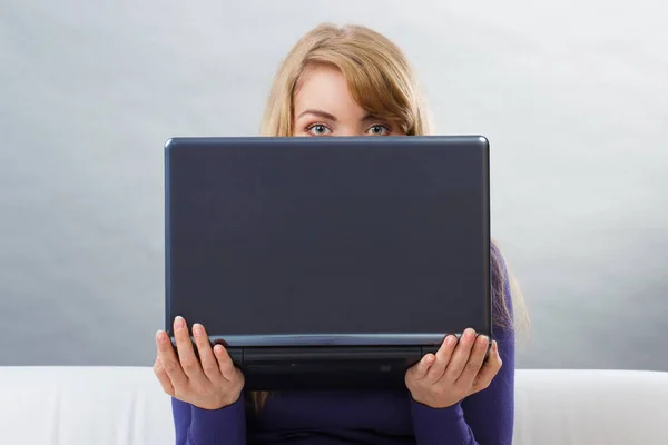 Mujer sosteniendo portátil y mirando hacia fuera desde detrás de la computadora — Foto de Stock