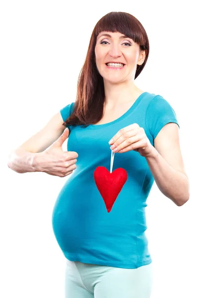 Gelukkige vrouw in zwangere rood hart te houden en het tonen van de duimen omhoog, begrip verwacht voor pasgeboren — Stockfoto