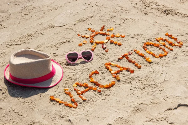 Palabra de vacaciones con forma de gafas de sol y sombrero de paja en la arena en la playa —  Fotos de Stock