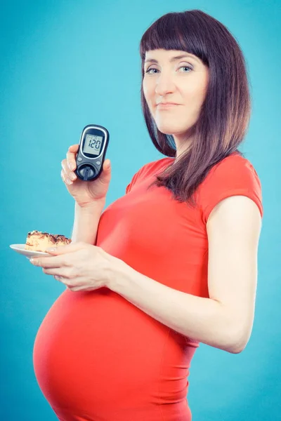 Femme enceinte tenant un glucomètre avec un taux de sucre et un gâteau au fromage, diabète pendant la grossesse — Photo