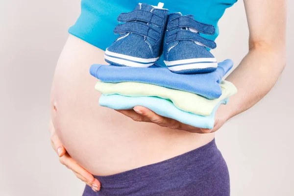 Zwangere vrouw met kleding voor pasgeboren, verwacht voor baby concept — Stockfoto