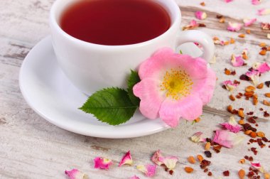 Çay ile eski rustik tahta üzerinde yabani gül çiçek