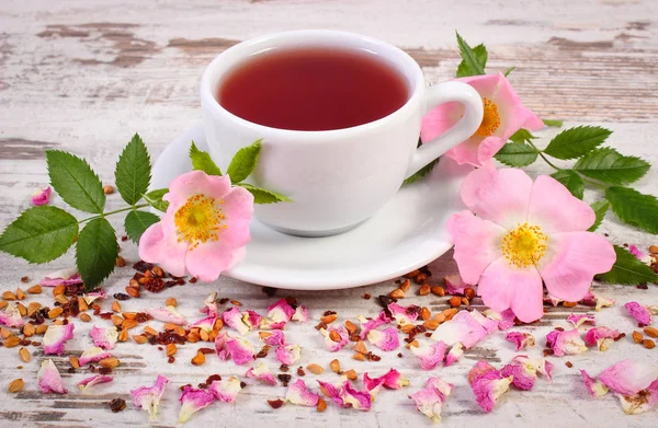 Kopje thee met wild rose bloem op rustieke houten achtergrond — Stockfoto