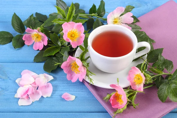 Kopje warme thee en wild rose bloem op de blauwe borden — Stockfoto