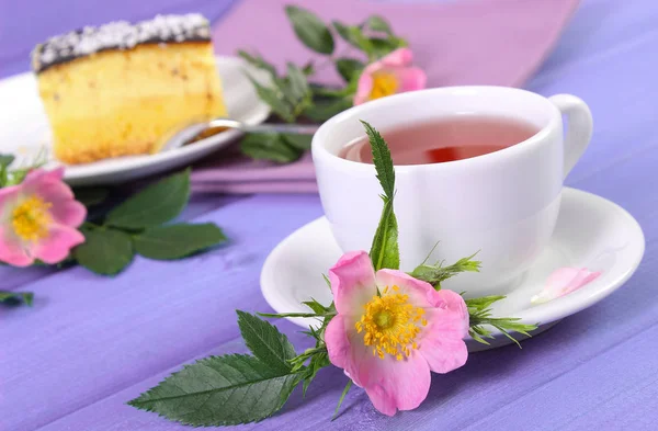 Tasse Tee mit Käsekuchen und Wildrosenblume auf Brettern — Stockfoto
