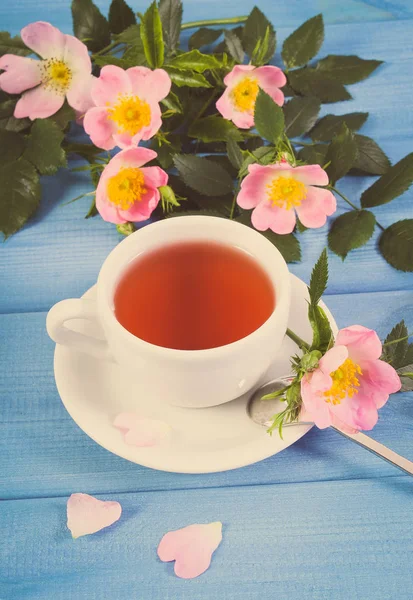 Vintage-Foto, Tasse Tee und Wildrosenblume auf Brettern — Stockfoto