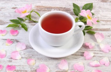 Fincan çay ve eski rustik tahta üzerinde yabani gül çiçek