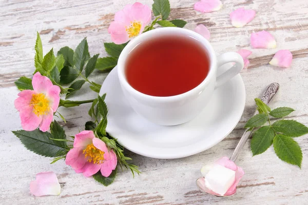 Xícara de chá e rosa selvagem flor no velho tabuleiro rústico — Fotografia de Stock