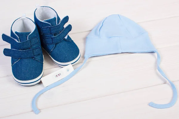 Zwangerschapstest met positief resultaat en kleding voor pasgeboren, verwacht voor baby concept — Stockfoto