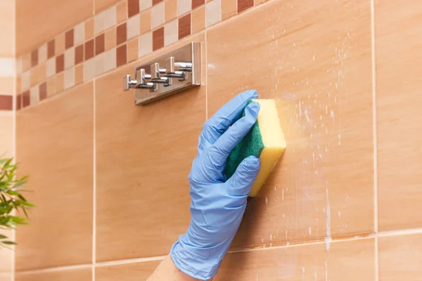 Рука женщины старшего возраста мойки плитки в ванной комнате с помощью губки с моющим средством, бытовые обязанности концепции — стоковое фото
