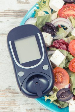 Glukometre ve peynirli Yunan salatası ve sebze. Şeker hastaları, diyet ve zayıflama için en iyi yiyecekler.