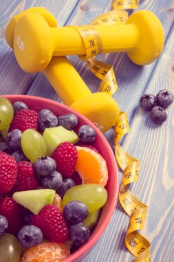 Taze meyve salatası ve santimetre dambıl, sağlıklı yaşam ve beslenme kavramı ile