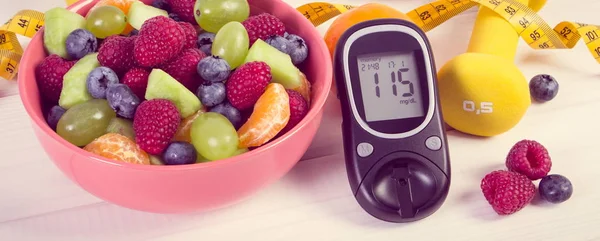 Fruit salad, glucometer, centimeter and dumbbells, diabetes, healthy lifestyle and nutrition concept