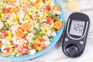 Şeker seviyesini ölçmek için glikoz ölçer, sebzeli salata ve kuskus ezmesi. Vitamin içeren şeker hastaları için hafif ve sağlıklı bir yemek