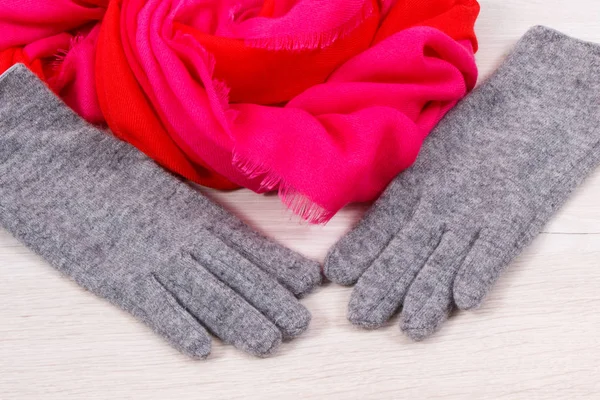 Paar graue warme Damenhandschuhe und buntes Tuch für den Einsatz im Herbst oder Winter — Stockfoto