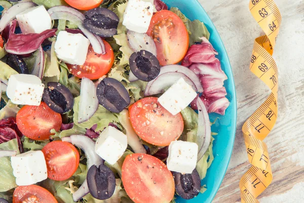 Cinta métrica y ensalada griega con queso feta y verduras como comida saludable que contiene vitaminas —  Fotos de Stock