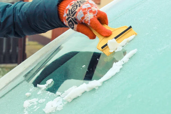 Ręka kobiety zeskrobującej lód z przedniej szyby samochodu. Problemy zimowe w transporcie — Zdjęcie stockowe