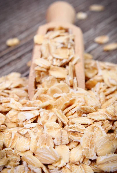 Oat flakes with wooden spoon. Healthy food containing dietary fiber. Wooden background