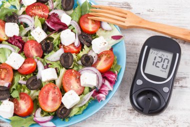 Şeker seviyesini ve taze Yunan salatasını kontrol etmek için glukometre. Diyabet ve sağlıklı yaşam tarzları