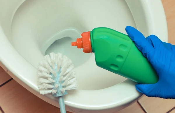 Mão em luva azul limpeza vaso sanitário usando escova e químico detegent — Fotografia de Stock