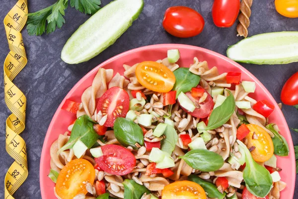 Cinta métrica y ensalada fresca con pasta integral y verduras. Estilos de vida saludables y nutrición —  Fotos de Stock