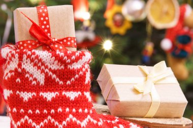 Noel arkaplanındaki Noel ağacında süslemeli çorap içinde paketlenmiş hediye.