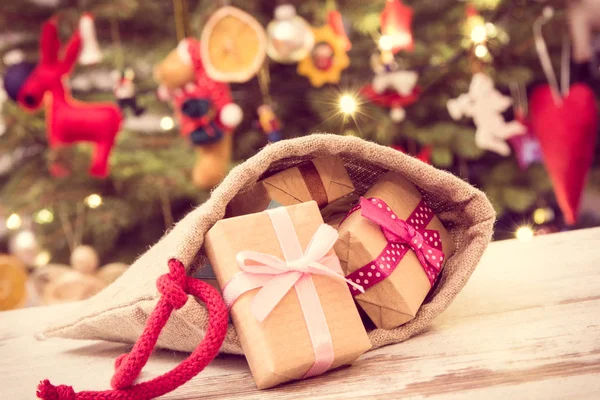 Vintage φωτογραφία, τυλιγμένα δώρα με κορδέλες σε τσάντα γιούτα για τα Χριστούγεννα και δέντρο με διακόσμηση, Χριστούγεννα έννοια του χρόνου — Φωτογραφία Αρχείου