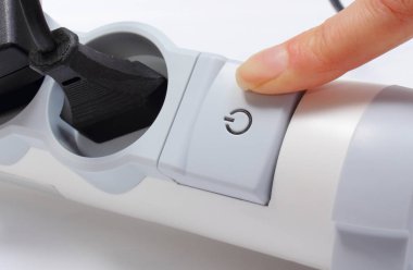 Kadının parmağı prizlerle elektrik uzantısını kapatıyor. Enerji tasarrufu kavramı