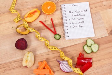 New year resolutions for 2019 and clock made of fruits with vegetables and tape measure