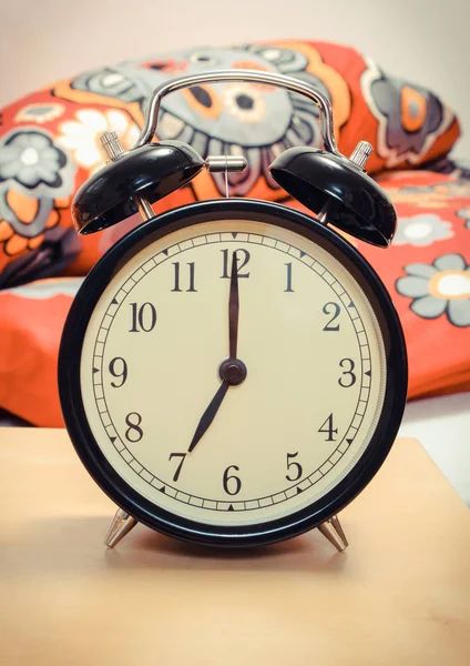 Ringing alarm clock and empty bed in background — Stock Photo, Image